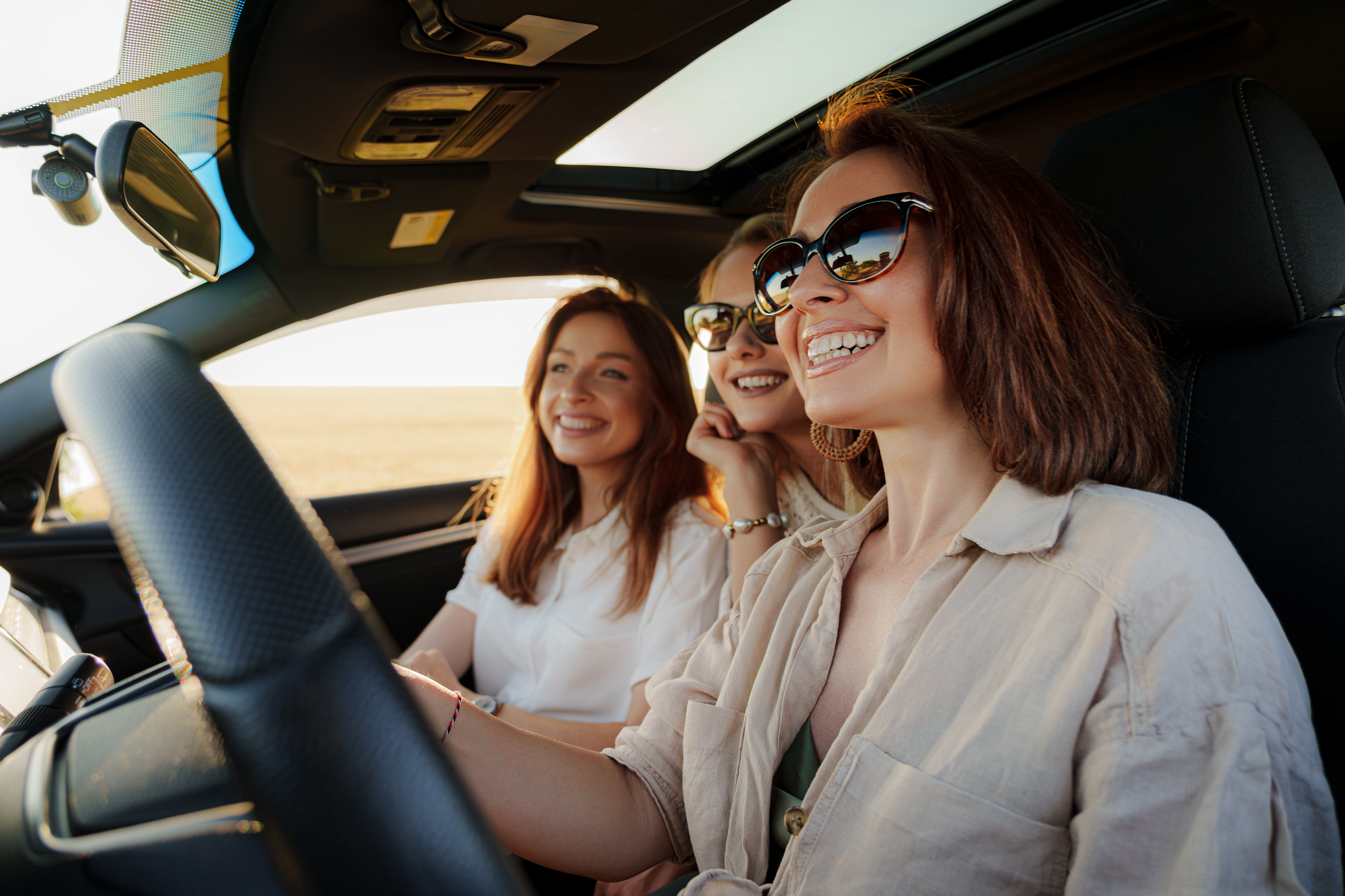 Cheerful women sitting in car while on vacation